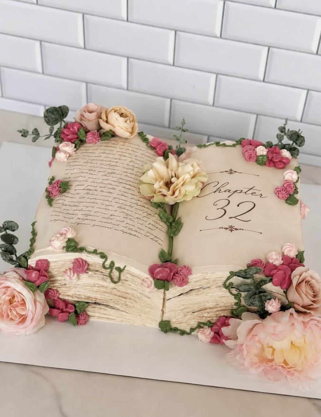 Elegant open-book fondant cake decorated with sugar flowers, reading 'Chapter 32', by Anny's Pastry Chicago