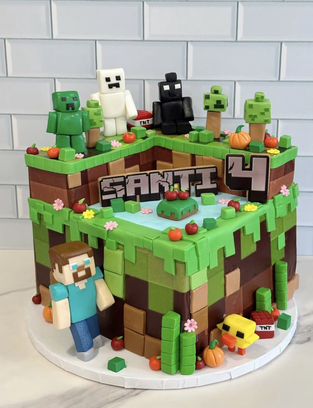 Minecraft grass-block themed birthday cake with fondant characters for a 4th birthday